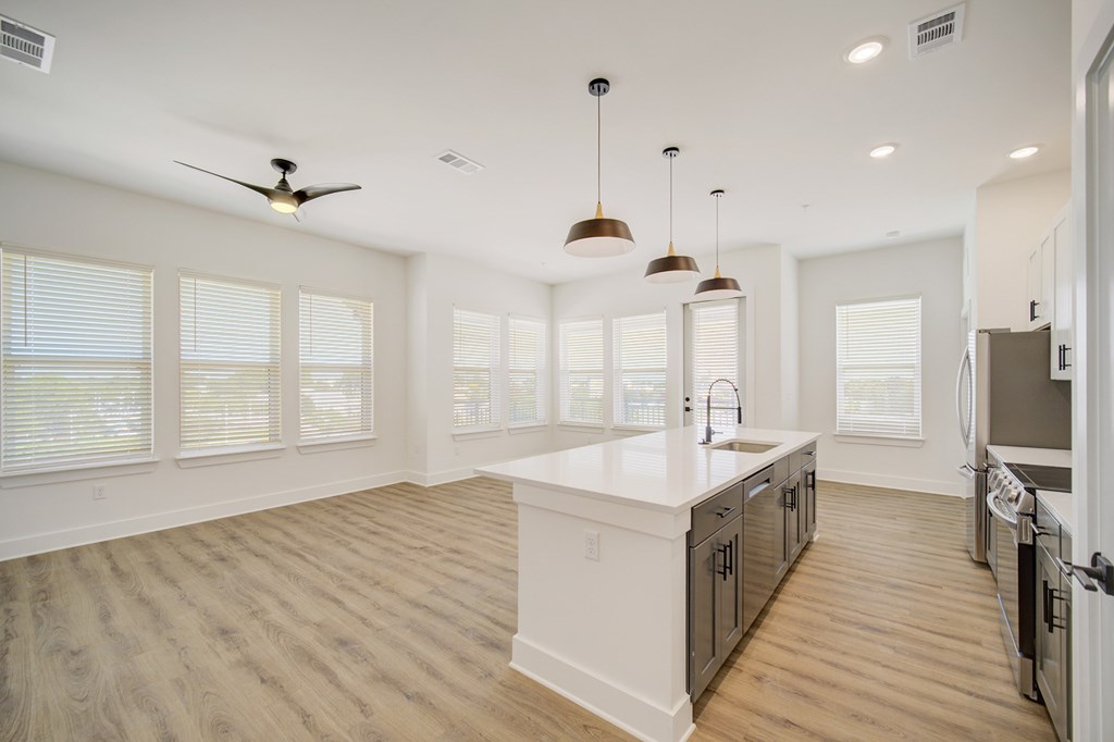 A spacious kitchen with a white countertop and wooden flooring.
