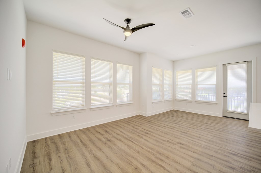 A room with a ceiling fan and wooden flooring.
