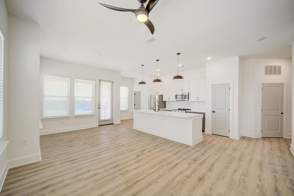 A spacious kitchen with a fan and wooden flooring.