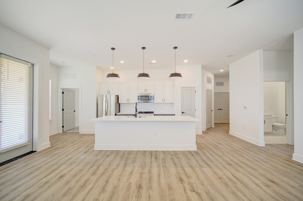 A spacious kitchen with a white island and pendant lights.