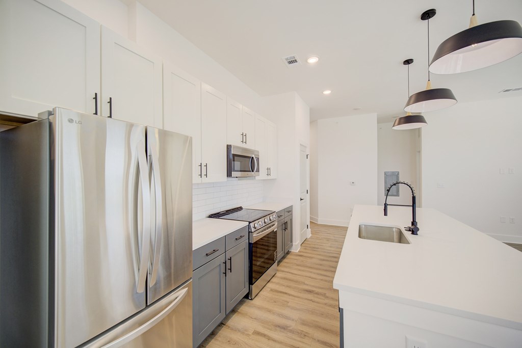 A modern kitchen with a stainless steel refrigerator and wooden floors.