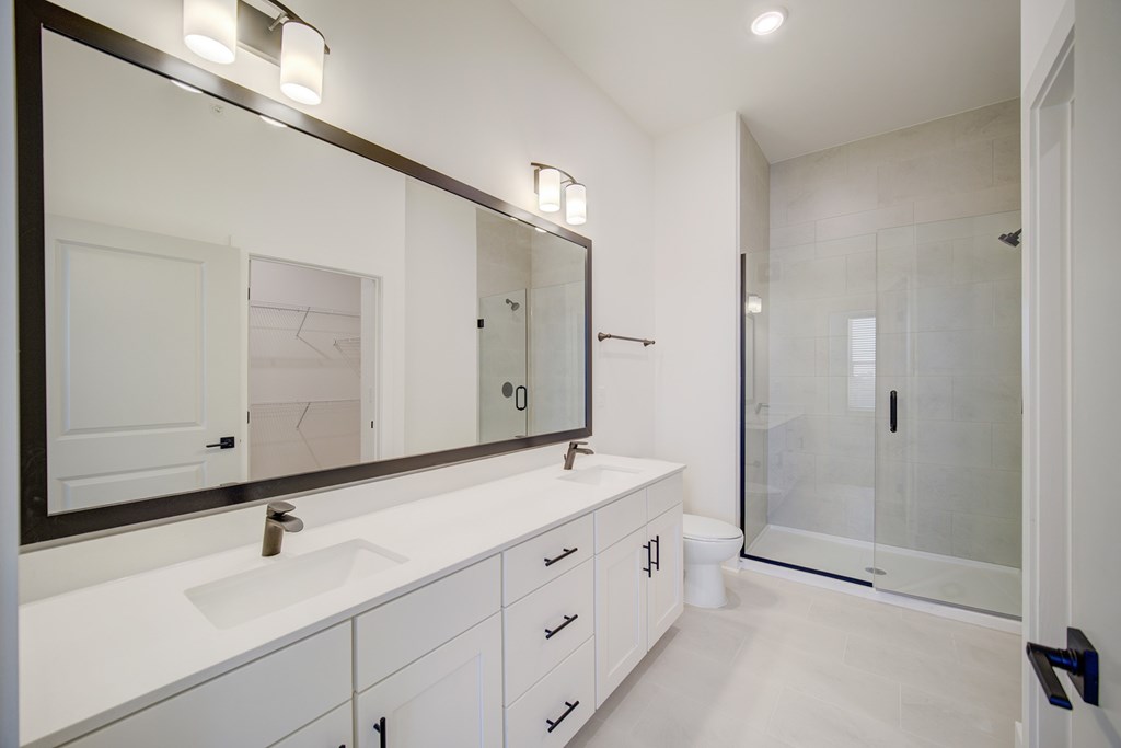 A white bathroom with a large mirror above a sink.