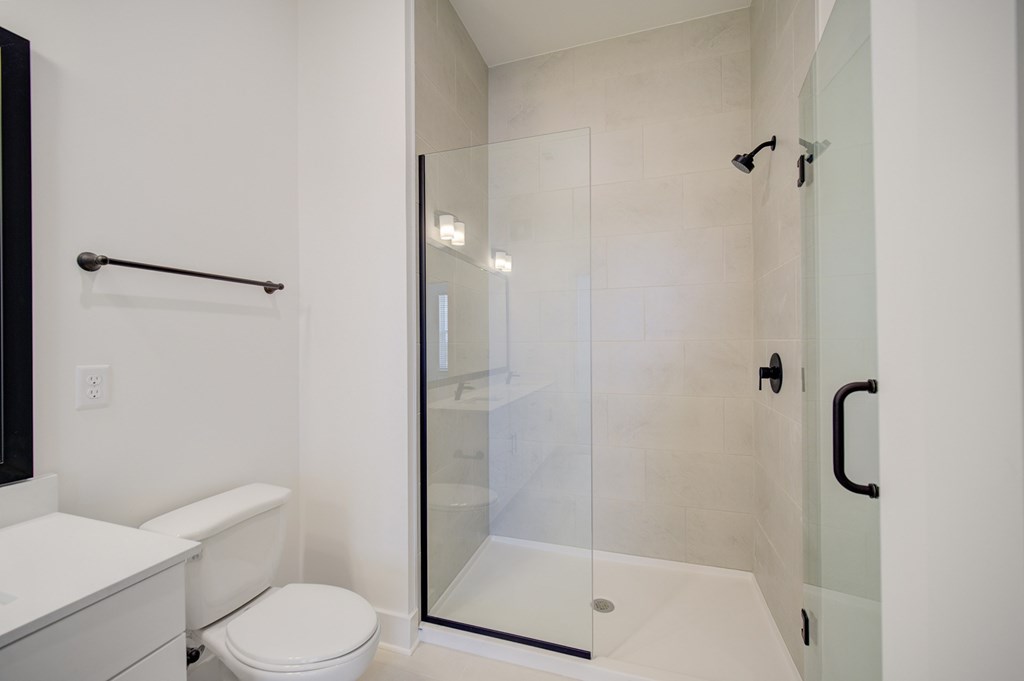 A white toilet sits next to a walk-in shower with a glass door.