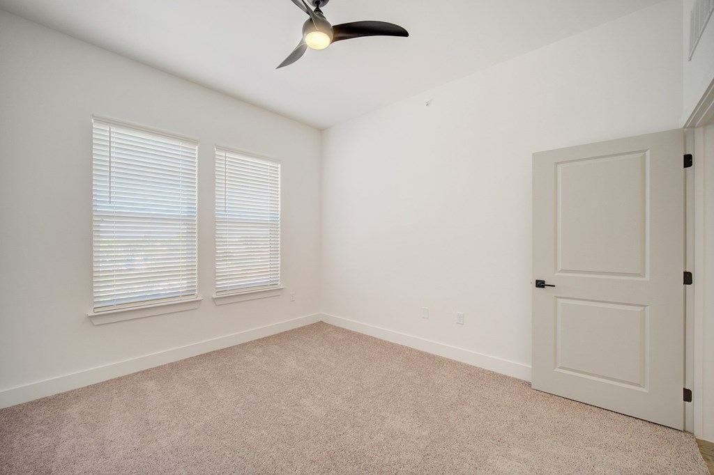 A room with a ceiling fan and a door.
