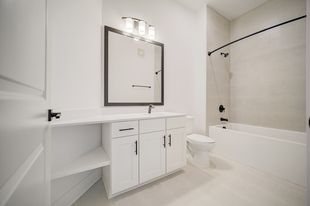 A white bathroom with a toilet, sink, and a mirror.