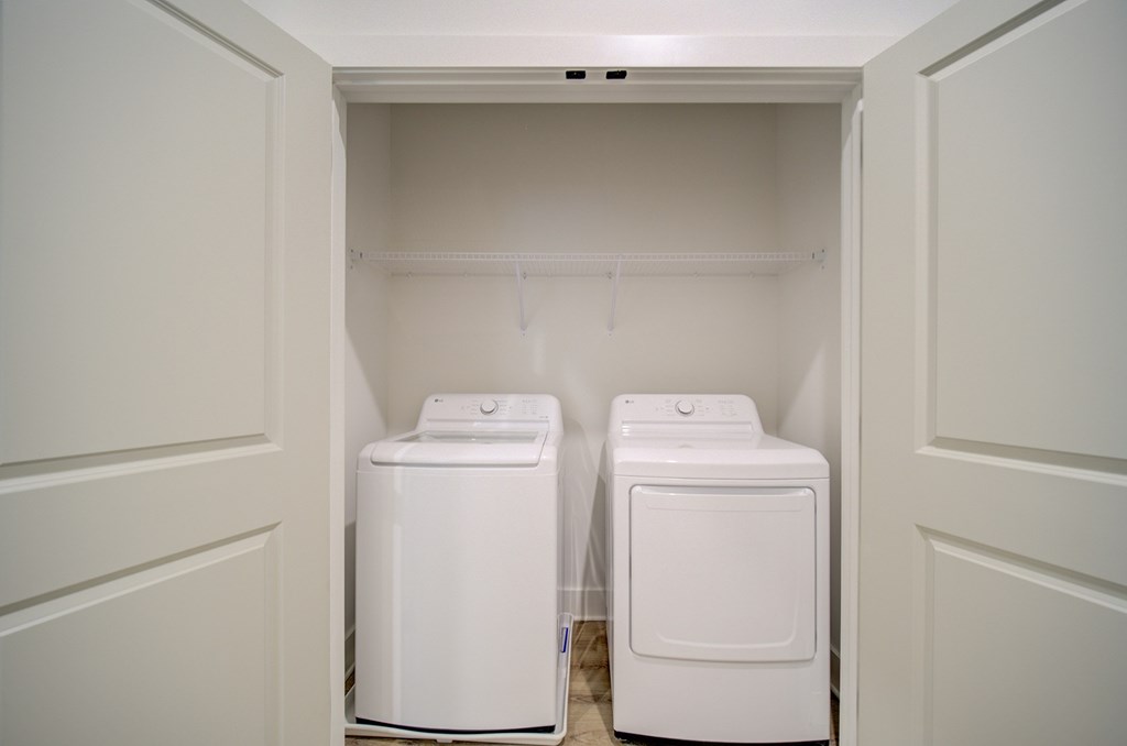 Two white front loading washing machines in a laundry room.
