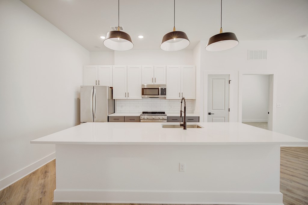 A kitchen with white cabinets and a white countertop.