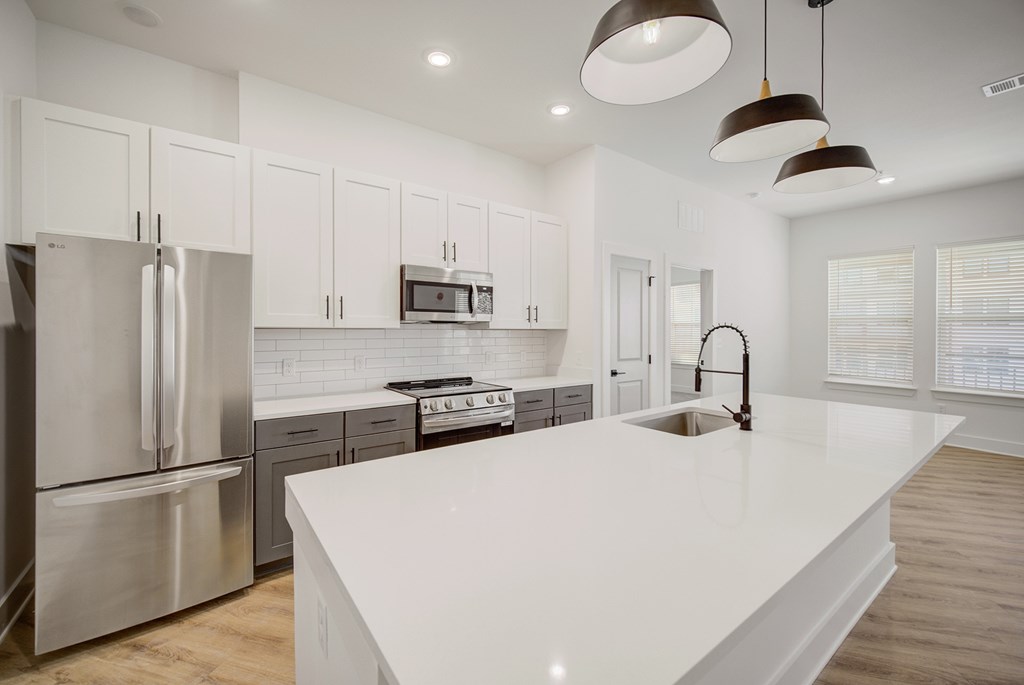 A modern kitchen with a white countertop and stainless steel appliances.