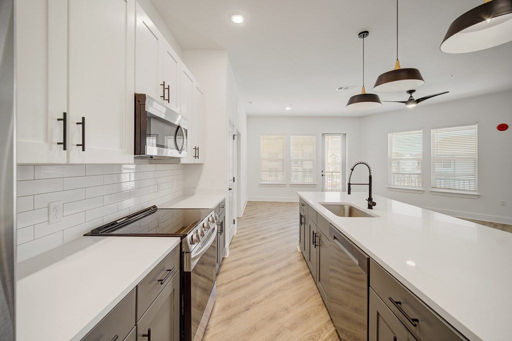 A modern kitchen with white cabinets and a wooden floor.