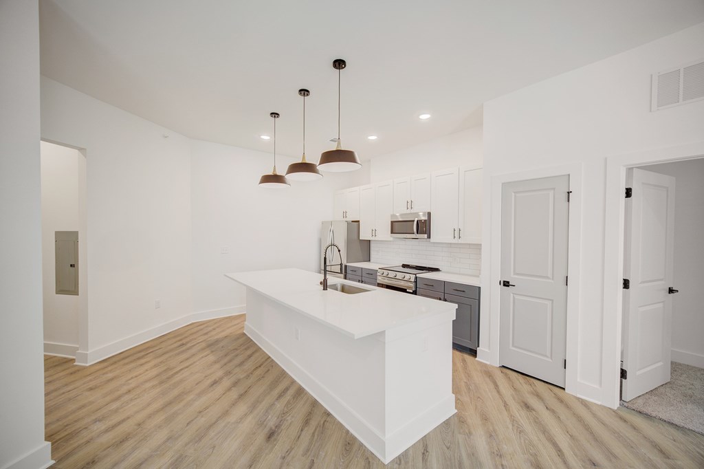 A kitchen with a white island and pendant lights.