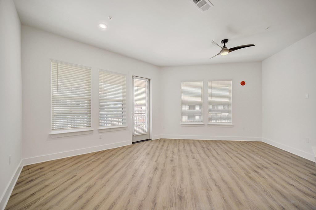 A room with a ceiling fan and wooden flooring.