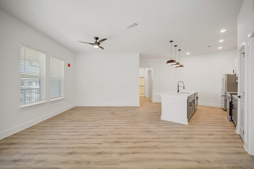 A spacious room with a ceiling fan and wooden flooring.