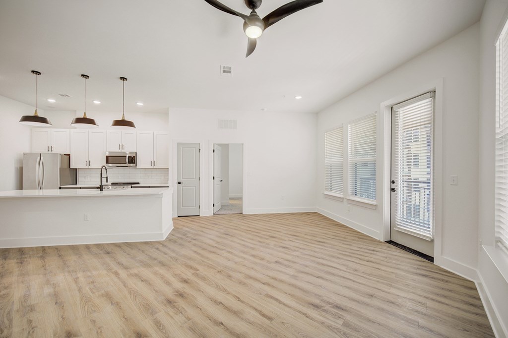 A spacious kitchen and living room with wooden floors and white walls.
