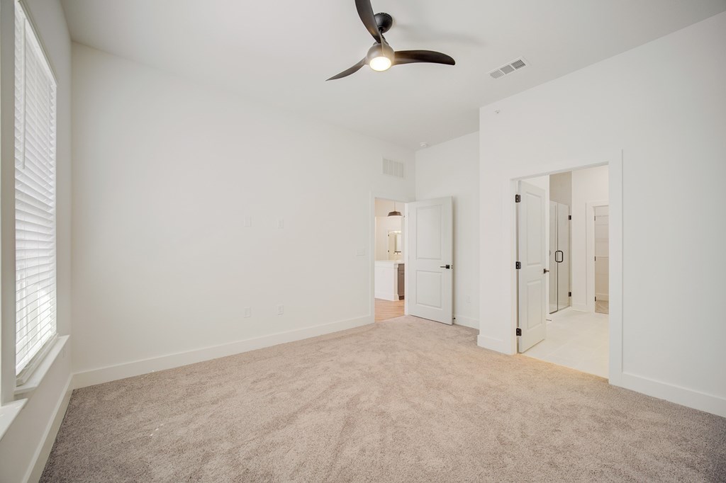 A room with a ceiling fan and carpeted floor.