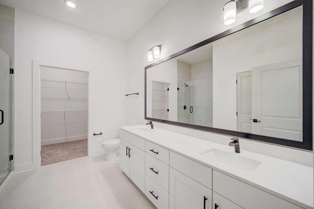 A white bathroom with a sink, mirror, and toilet.