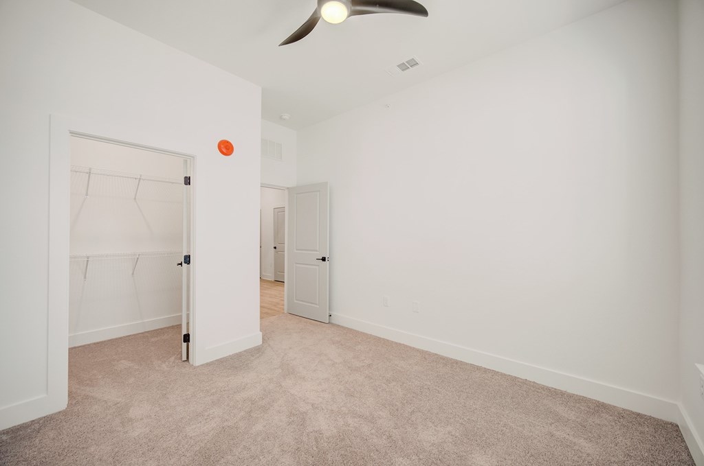A room with a carpeted floor and a ceiling fan.