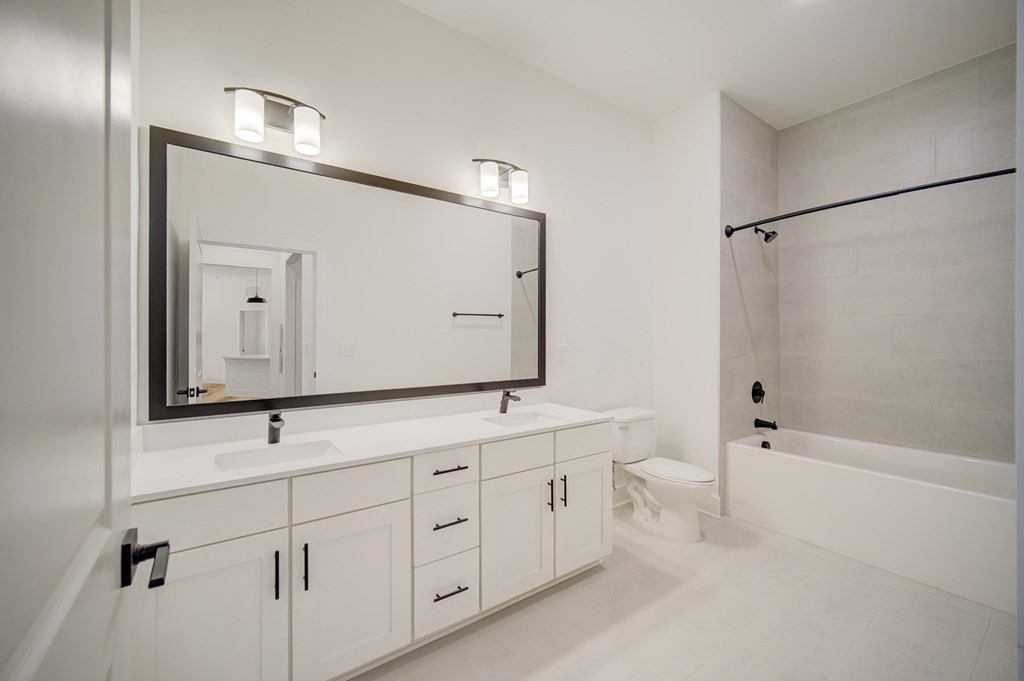 A bathroom with a white sink and a large mirror.