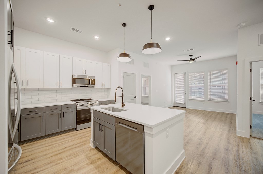A modern kitchen with a white island and wooden floors.