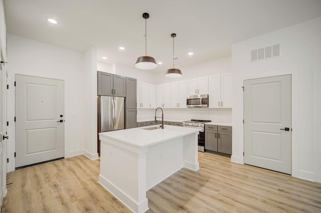 A kitchen with a white island and wooden floors.