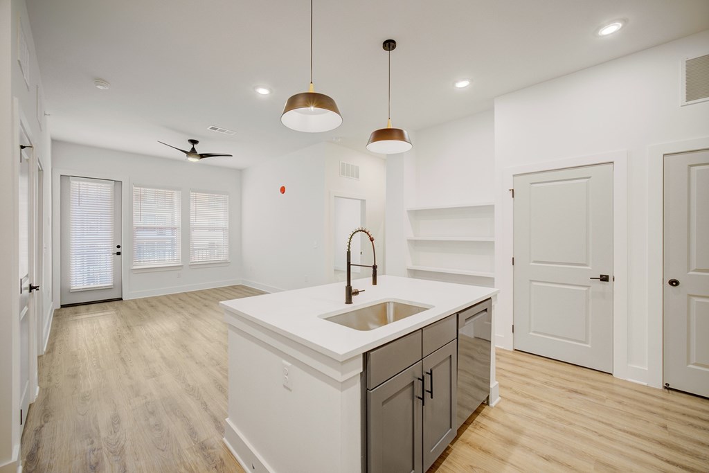 A modern kitchen with a white countertop and wooden flooring.
