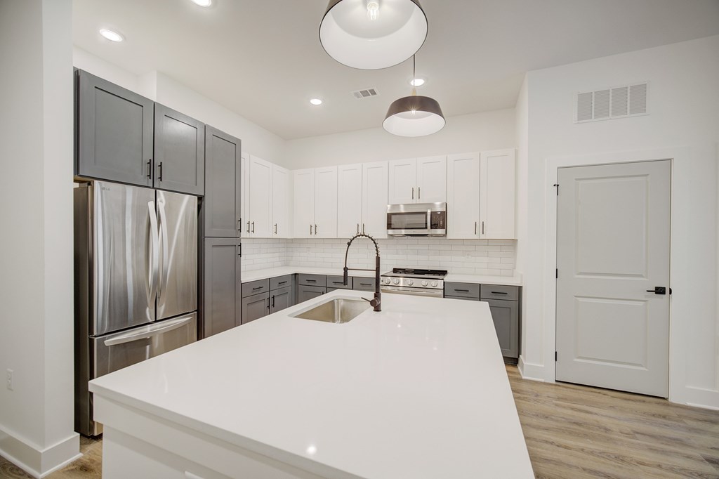 A modern kitchen with a white countertop and stainless steel appliances.