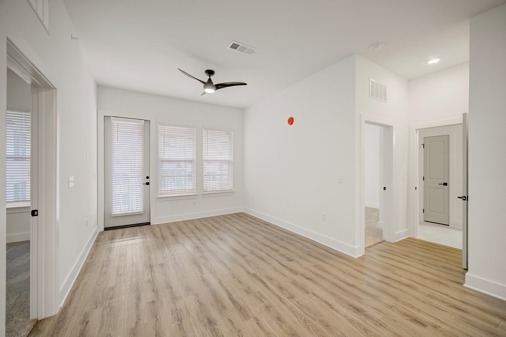 A room with a ceiling fan and wooden flooring.