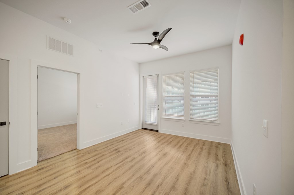 A room with a ceiling fan and wooden flooring.