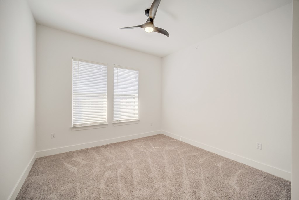 A room with a ceiling fan and carpeted floor.