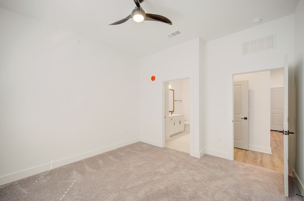A room with a ceiling fan and a carpeted floor.