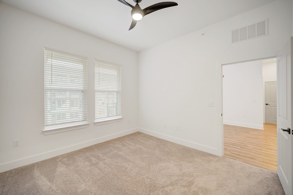 A room with a ceiling fan and carpeted floor.