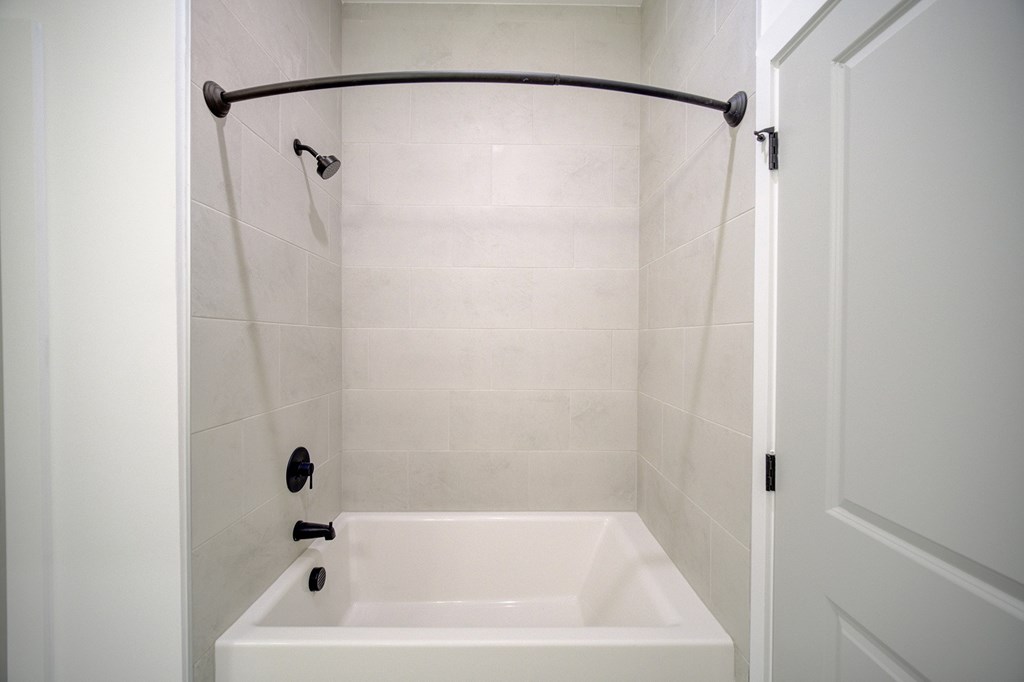 A white bathroom with a white tub and a white shower curtain.