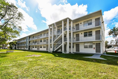 A white apartment building with a green lawn in front.