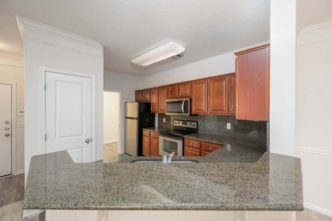 A kitchen with granite countertops and wooden cabinets.