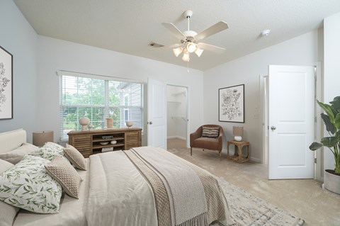 A bedroom with a large bed and a ceiling fan.