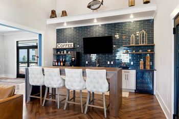 a kitchen with a bar with white chairs and a blue tile wall