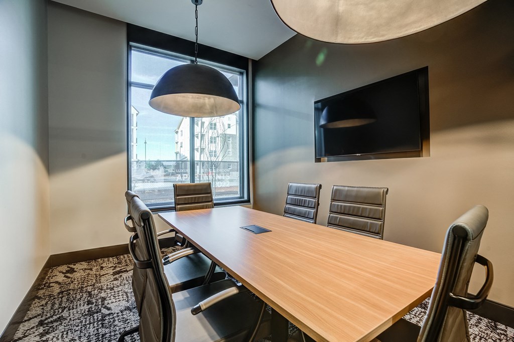 a meeting room with a large window and a wooden table and chairs