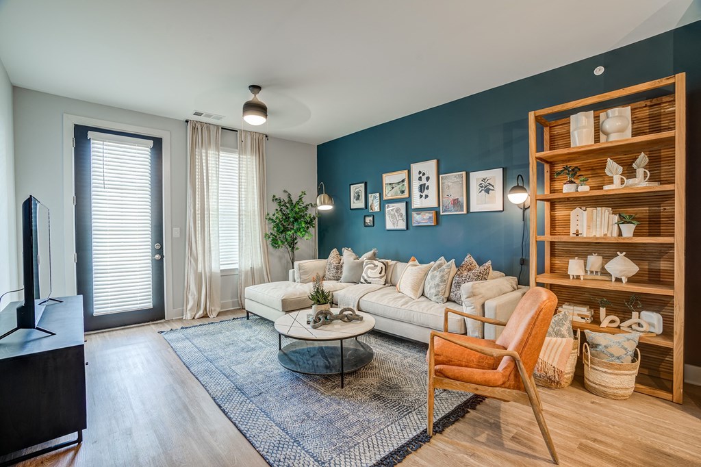 1 Bedroom Apartments in Madison, Alabama - The Dempsey - Living Room with Sectional Couch, Large Windows, and Light Wood Flooring.