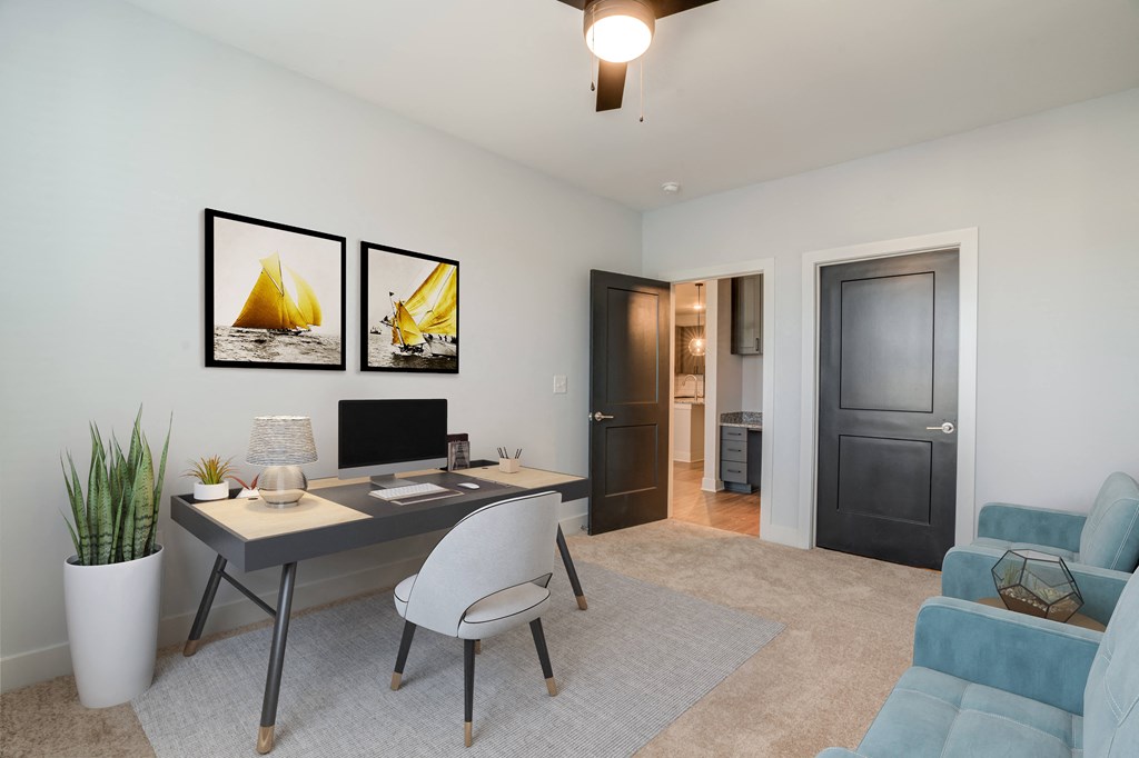 a living room with a desk with a computer and a couch
