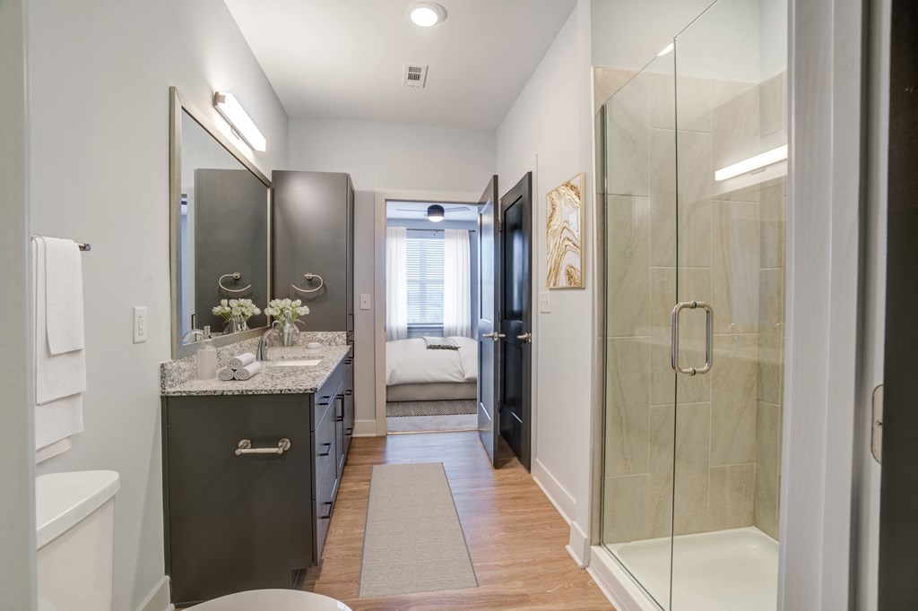 a bathroom with a shower and sink and a door to a bedroom