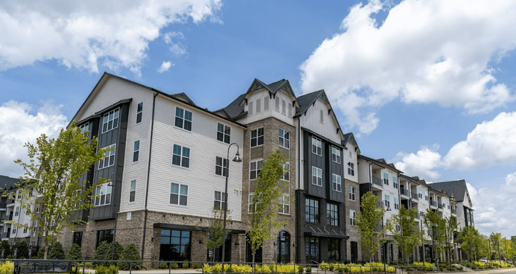 a large apartment building with a cloudy blue sky in the background