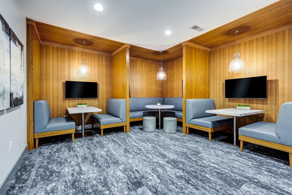 a lounge area with chairs and tables and televisions