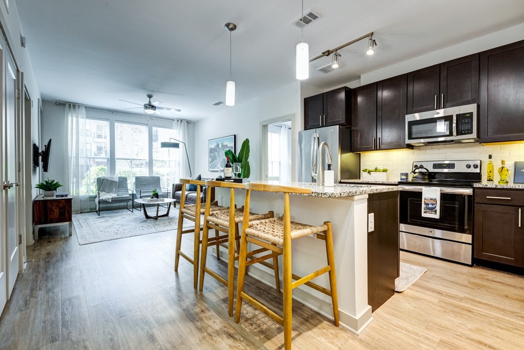 an open kitchen and living room with a bar and wooden stools