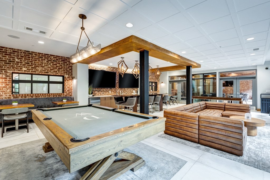 a pool table in a clubhouse with a bar and tables