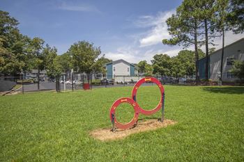 A red sculpture of three interlocking rings sits in a grassy field.