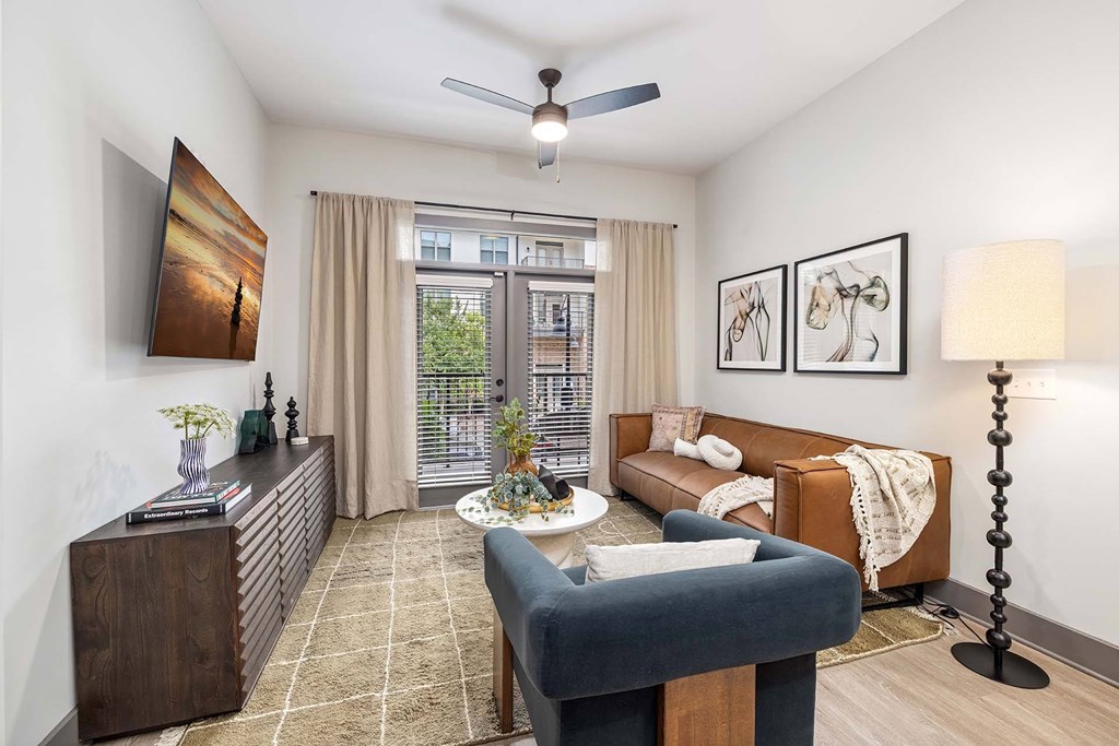 A living room with a blue couch, a coffee table, and a ceiling fan.