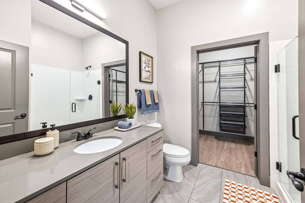 A bathroom with a toilet, sink, and mirror.