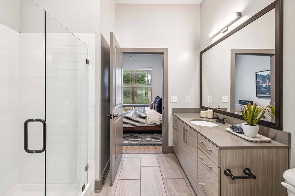 A bathroom with a glass shower door and a wooden vanity.