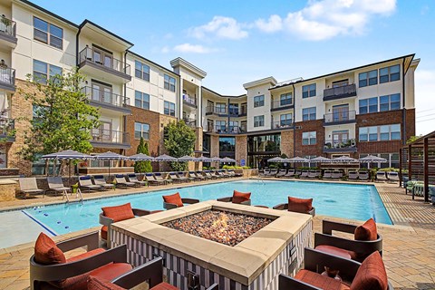 Dog-Friendly Apartments in Duluth, GA - District at Duluth - Swimming Pool With Lounge Chairs, Umbrellas, Fire Pit Seating, and Landscaped Courtyard.