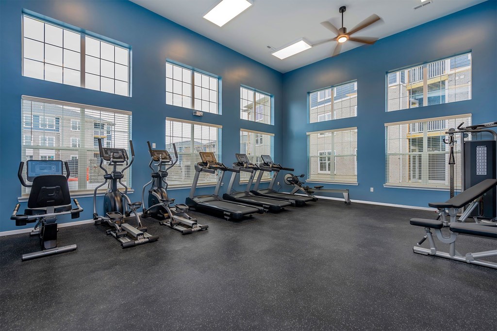 A spacious gym with a variety of equipment and large windows.
