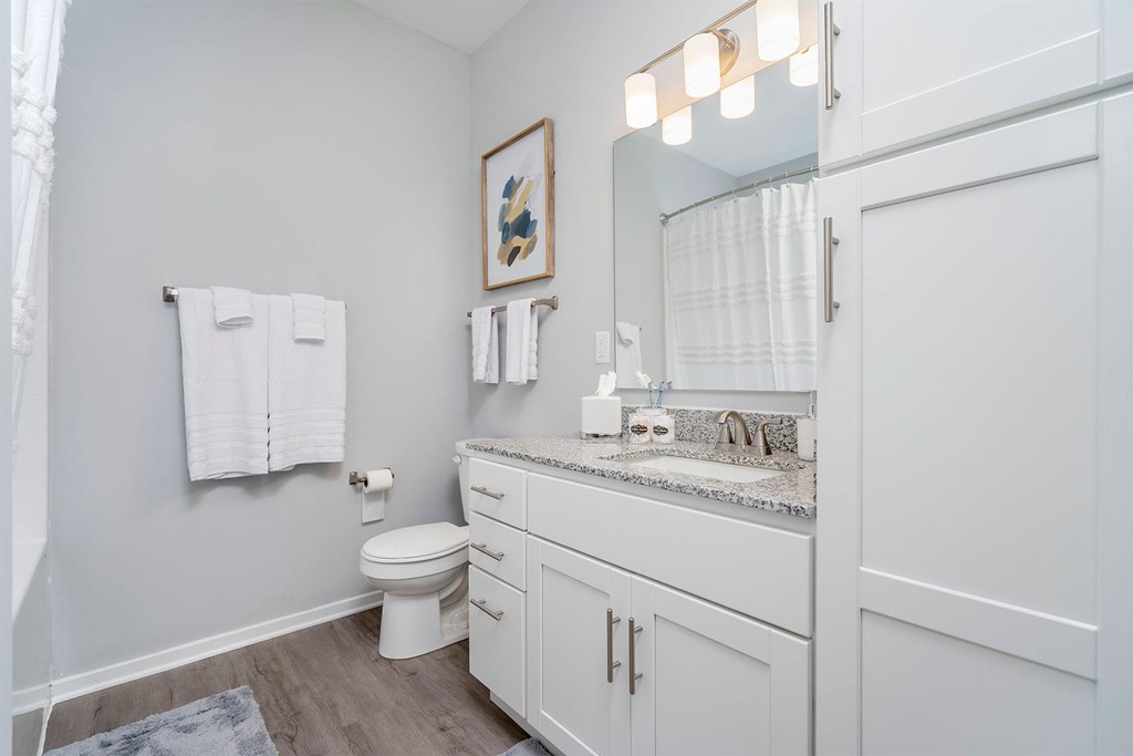 A white bathroom with a toilet, sink, and mirror.